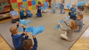grupa dzieci bawi sie na dywanie niebieskimi workami