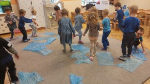 grupa dzieci bawi sie na dywanie z niebieskimi workami