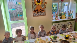 dzieci siedą przy świątecznym stole za plecami mają drzwi na taras przedszkolny na ścianie wisi obrazek tygryska