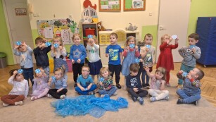 dzieci pozują do zdjęcia w sali przedszkolnej stojąc i siedząc trzymają w rękach narysowane kropelki wody