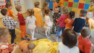 dzieci bawiące się na sali przedszkolnej, ubrane w tonacji pomarańczowej