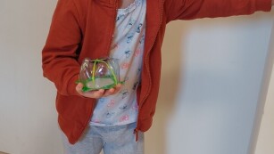 na zdjęciu dziewczynka z eko zabawką, trzyma w ręku żółwika z butelki
