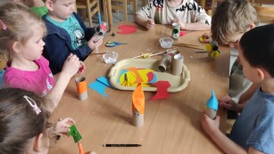 Dzieci przy stolikach wykonują prace plastyczno-techniczne