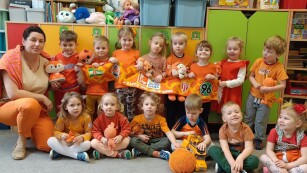 grupa dzieci z panią pozują do zdjęcia, większość ubrana w kolorach pomarańczu