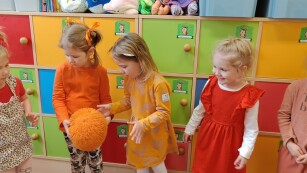 grupa dzieci bawią się pomaranczową piłką