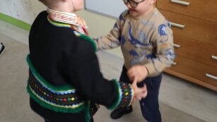 dzieci tańczą trzymając się za rękę, chłopiec ubrany jest w strój ludowy