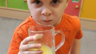 chłopiec na zdjęciu pije sok pomarańczowy