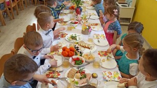 dzieci częstują się potrawami przygotowanymi na śniadanie wielkanocne