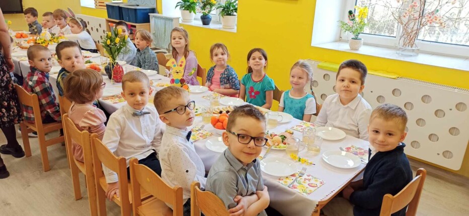 dzieci siedzą przy stoliku nakrytym odświętnie