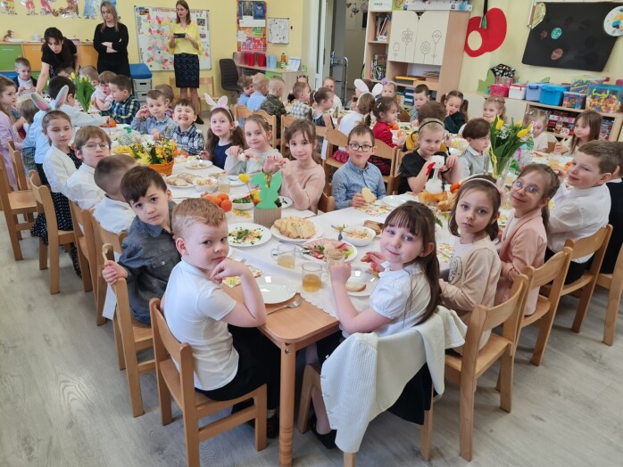 grupa dzieci patrzy w obiektyw siedząc przy świątecznym stole dzieci elegancko ubrane