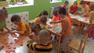 Dzieci przy stolikach pracują w grupach, układają puzzle, układają kompozycje z marchewki