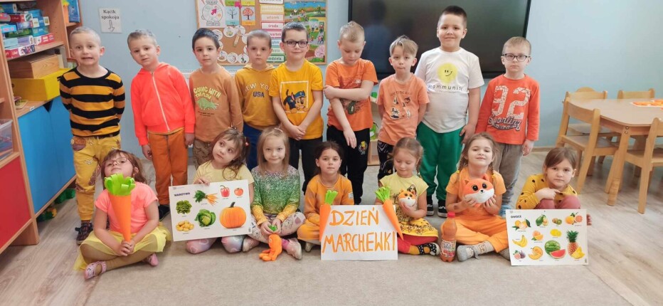 Dzieci z grupy Zajączki ubrane na pomarańczowo pozują do zdjęcia