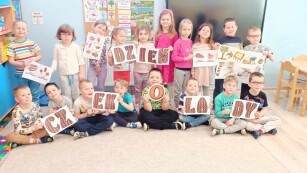 Cała grupa dzieci z grypy Zajączki pozuje z napisem  dzień czekolady