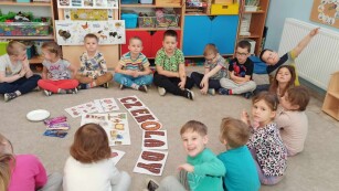 Dzieci siedzą w kole w którym są rozłożone materiały do zajęć na dzień czekolady