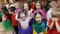 grupka dzieci ubranych w kolorowe koszulki stoi w dwóch rzędach dzieci patrzą w kamerę